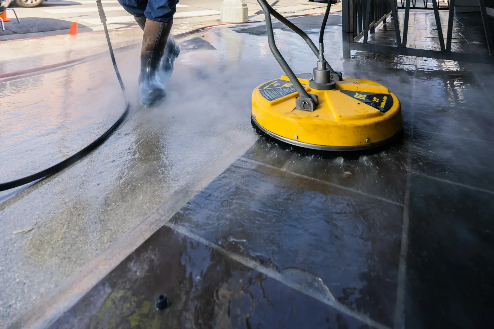 Surface cleaner washing gray film off a wet concrete walkway